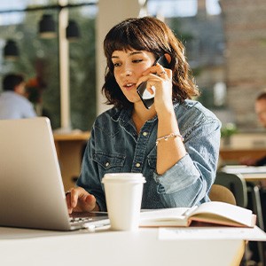 Woman talking on phone while working on laptop