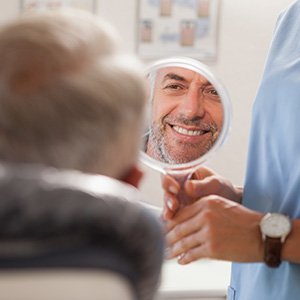 Patient smiling at reflection in handheld mirror