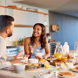 Couple smiling at each other while eating in kitchen