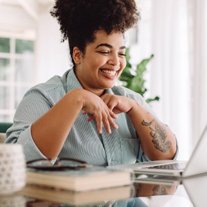 Woman smiling while working on laptop at home